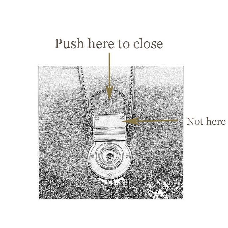 May include: Close-up of a leather bag's clasp. The clasp has a metal latch with a small keyhole. The text "Push here to close" is above the clasp, and "Not here" is to the right of the clasp.