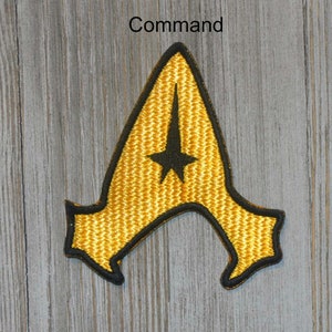 May include: A yellow embroidered patch with a black outline in the shape of a stylized letter A with a black five-pointed star in the center. The text "Command" is above the patch.