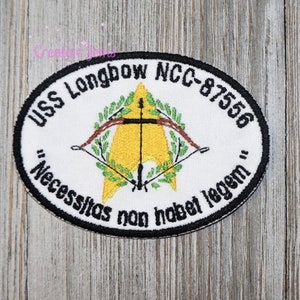 May include: A white embroidered patch with a black border. The patch features a yellow starfleet insignia with a bow and arrow crossing in front of it. The text "USS Longbow NCC-87556" is written around the top of the patch. The text "'Necesitas non habet legem'" is written around the bottom of the patch.
