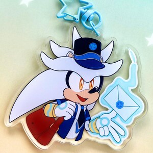 May include: A clear acrylic keychain featuring a cartoon character with silver fur, wearing a blue and black hat and a blue vest. The character holds a white envelope with a blue wax seal, surrounded by a light blue flame effect, attached to a star-shaped clasp.