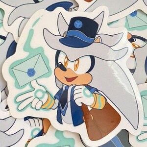May include: A sticker featuring a cartoon silver hedgehog wearing a blue and white hat and a blue jacket. The hedgehog is holding a blue and white envelope with a blue seal. The sticker is on a white background.