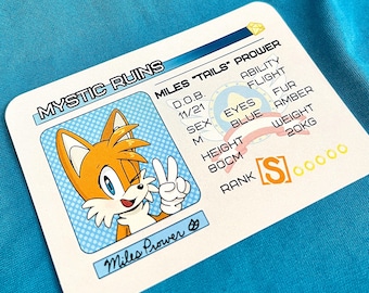 Puede incluir: Una tarjeta blanca con el personaje Miles "Tails" Prower de la serie Sonic the Hedgehog. La tarjeta incluye el texto "MYSTIC RUINS" y detalles del personaje como la altura (80cm), el peso (20kg) y el color de ojos (azul).