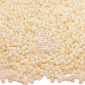 May include: A large pile of small, white, round beads. The beads are all the same size and shape, and they are arranged in a random pattern.