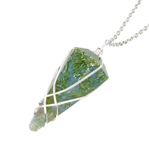 May include: A pendant necklace featuring a green and blue moss agate crystal wrapped in silver-colored wire. The crystal is a long, pointed shape, suspended from a delicate silver chain. The pendant is set against a white background.