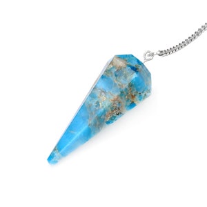 May include: A blue and brown crystal pendulum with a silver chain. The crystal is a light blue color with brown marbling. The pendulum is a pointed shape, and the chain is attached to the top.