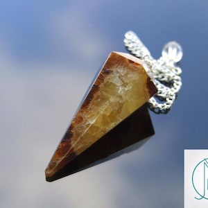 May include: A brown and yellow crystal pendulum with a silver chain. The pendulum is shaped like a point and has a natural, rough texture.