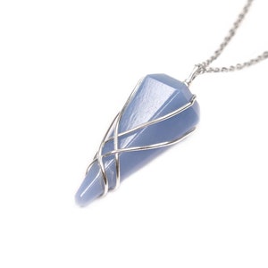May include: A blue-grey crystal pendant necklace. The crystal is a faceted, elongated shape, wrapped in silver-coloured wire. The chain is also silver-coloured, and the background is white.