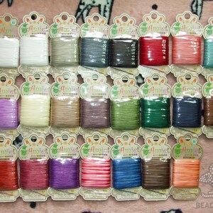 May include: A collection of 36 spools of embroidery floss in various colours, including purple, pink, red, green, blue, brown, and white. Each spool is labelled "Amiet" and has a number on it.