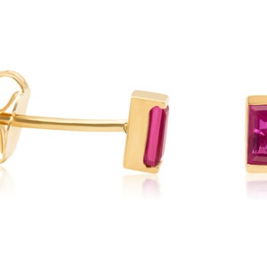 May include: A pair of gold earrings with a pink rectangular gemstone in each earring.