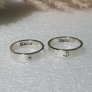 May include: Two silver rings with engraved names, "Macie" and "Sami", and a sun and moon design.