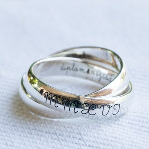 May include: A silver ring with three bands intertwined. The inscription "diplomatized" is visible on the inside of the ring. The inscription "MMXVG" is visible on the outside of the ring.