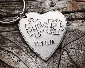 Op de afbeelding: Zilveren hartvormige sleutelhanger met een puzzelstukontwerp en de datum 11.11.14 erop gegraveerd.