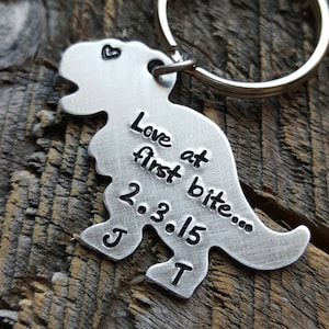 May include: Silver dinosaur keychain with the text "Love at first bite... 2.3.15 J T" engraved on it.