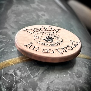 K&ouml;nnte beinhalten: Eine runde Holzscheibe mit dem Text "Daddy, I'm so proud" und einem Handabdruck in einem Dreieck mit dem Text "13 years 02.25.12"