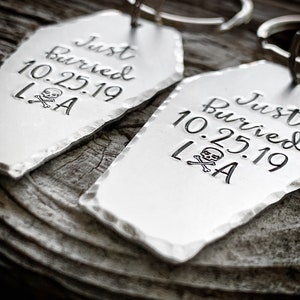 May include: Two silver coffin-shaped keychains with the text "Just Buried 10.25.19 LA" and a skull and crossbones graphic.