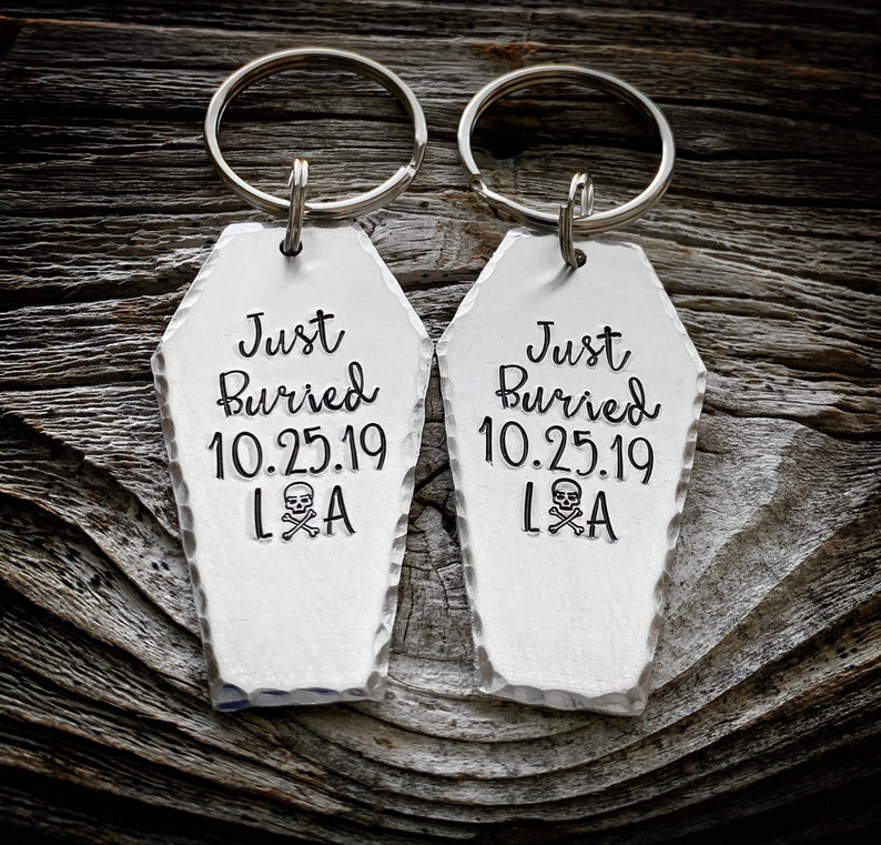 May include: Two silver coffin-shaped keychains with the text "Just Buried 10.25.19 L&A" and a skull and crossbones graphic.