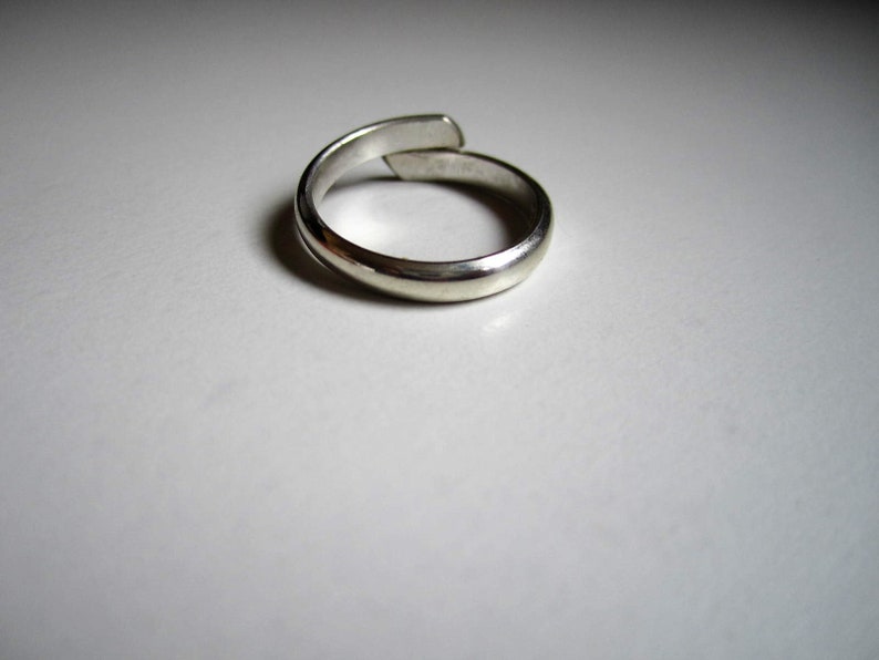 May include: A silver ring with a simple, smooth design. The ring is made of metal and has a polished finish.
