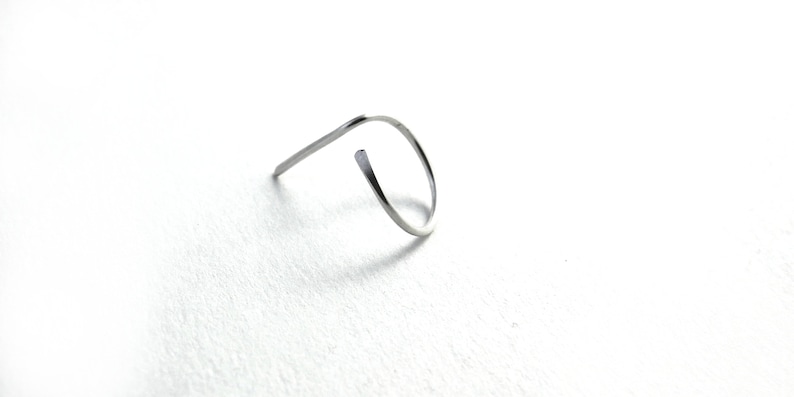 May include: A silver metal ring with a simple, curved design.