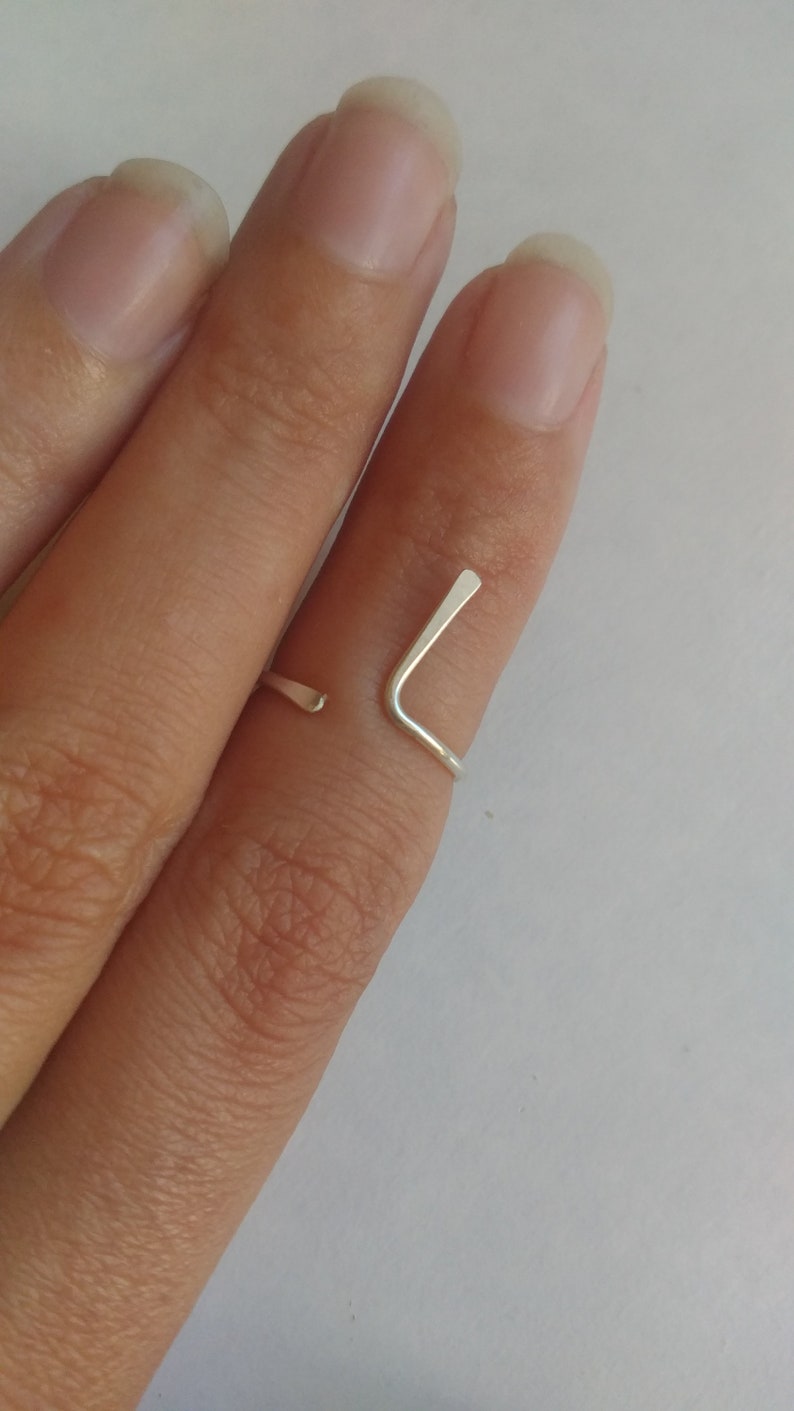 May include: A silver ring with a simple, minimalist design. The ring is made of a single piece of metal that is bent into a V-shape.
