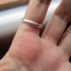 May include: A silver band ring worn on a finger.