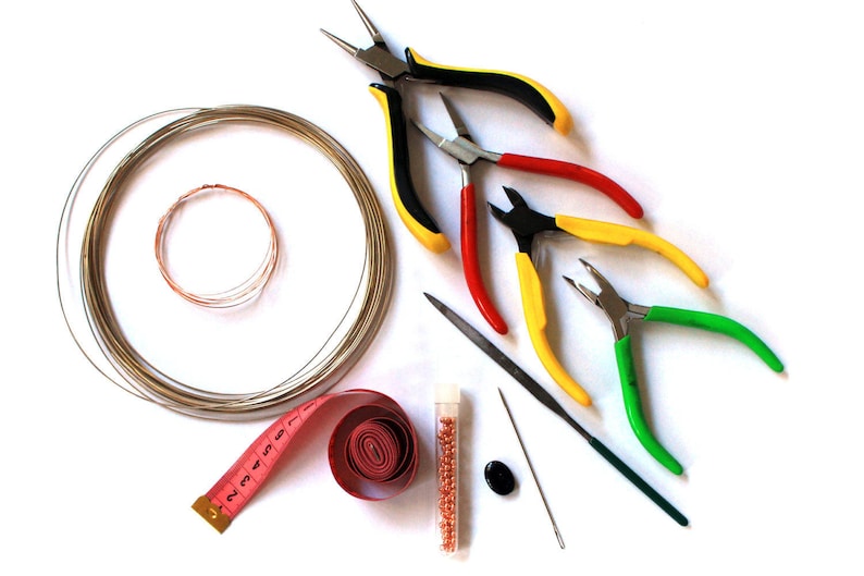 May include: A set of jewelry making tools including wire cutters, pliers, a needle, a measuring tape, a spool of wire, and a small container of beads.