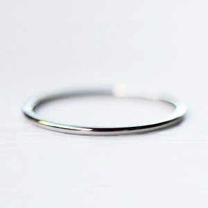 May include: A simple silver band ring.