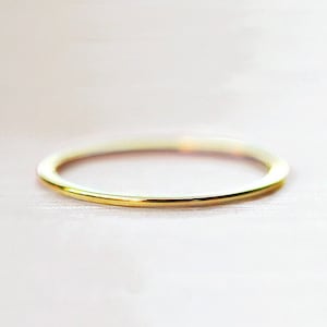 May include: A simple gold band ring.