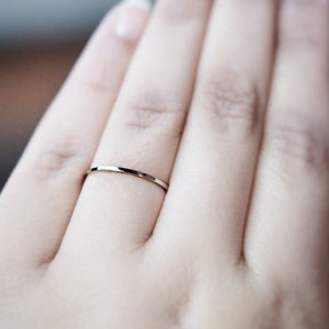 Pu&ograve; includere: Primo piano di una mano con un anello sottile a fascia d'argento.