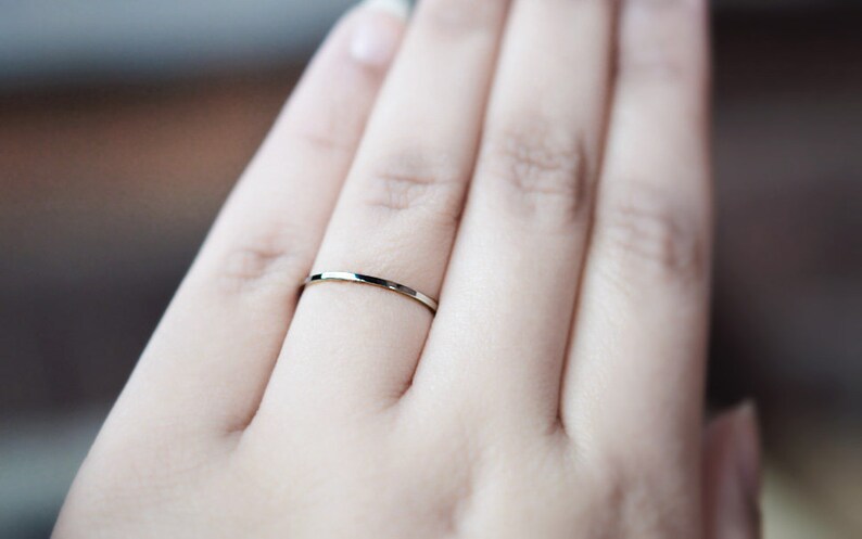 Pu&ograve; includere: Primo piano di una mano con un anello sottile a fascia d'argento.