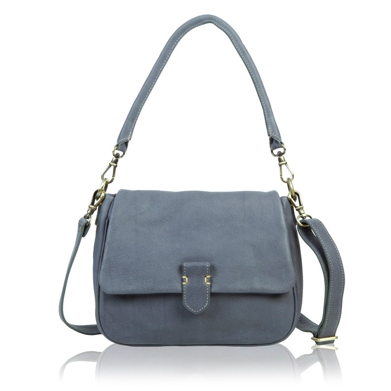 May include: A gray leather shoulder bag with a flap closure and a gold-toned buckle. The bag has a long adjustable strap.
