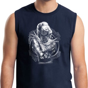Puede incluir: Camiseta sin mangas azul marino con un gráfico en blanco y negro de una mujer con tatuajes y un pañuelo que le cubre la cara. El gráfico está rodeado por un diseño de dinero y engranajes.