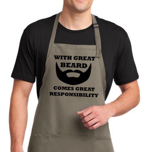 May include: A khaki apron with a black graphic that reads "With Great Beard Comes Great Responsibility". The graphic includes a black beard icon.