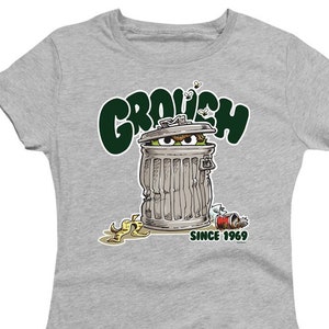 Może przedstawiać: Szary T-shirt z zieloną, ż&oacute;łtą i czarną ilustracją Oskara Gniewka z Ulicy Sezamkowej. Oskar znajduje się w śmietniku z napisem "Grouch" nad nim i "Since 1969" pod nim.