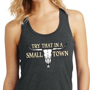 May include: A dark gray tank top with the text "Try that in a small town" and a white bull skull graphic.