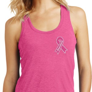 以下が含まれることがあります： ピンクのタンクトップにピンクのリボンと白い文字で「Survivor」と書かれています