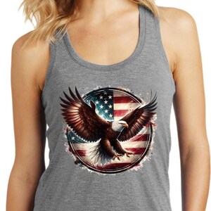 May include: A gray tank top with a graphic of a bald eagle flying in front of an American flag. The eagle is brown and white with a yellow beak. The flag is red, white, and blue.
