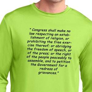 May include: A bright green long-sleeved shirt with the text "Congress shall make no law respecting an establishment of religion, or prohibiting the free exercise thereof; or abridging the freedom of speech, or of the press; or the right of the people peaceably to assemble, and to petition the Government for a redress of grievances."