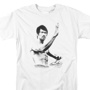 May include: A white t-shirt with a black and white image of Bruce Lee in a martial arts pose. The image is accompanied by Bruce Lee's signature.