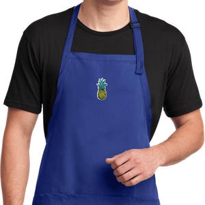以下が含まれることがあります： 大きなポケットとパイナップルの刺繍デザインが施されたロイヤルブルーのエプロンです。