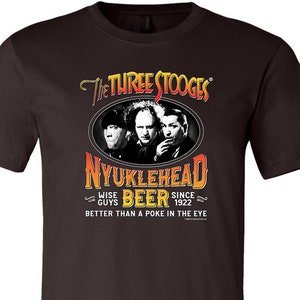 May include: A brown t-shirt with a graphic of the Three Stooges and the text "The Three Stooges", "Nyuklehead Beer", "Wise Guys", "Since 1922", and "Better than a poke in the eye".
