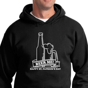 Peut inclure: Sweat-shirt à capuche noir avec un graphique blanc d'une bouteille de bière et d'une chope avec le texte "Beer Me! Happy St. Patrick's Day"