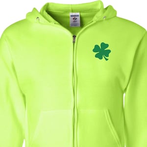 Puede incluir: Una sudadera con capucha de color verde neón brillante con un trébol de cuatro hojas verde en el pecho izquierdo.