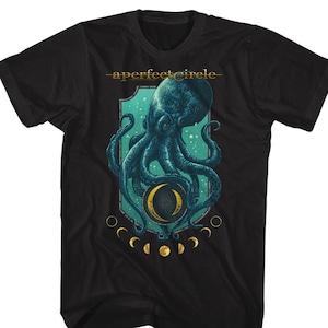 May include: Black t-shirt with a graphic of an octopus holding a crescent moon in a crest with the text "a perfect circle" above the crest. The crest is surrounded by a ring of crescent moons.