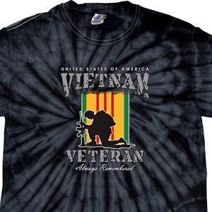 Peut inclure: T-shirt noir tie-dye avec une silhouette de soldat agenouillé tenant un fusil. Le t-shirt porte l'inscription "United States of America Vietnam Veteran Always Remembered".