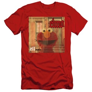 Puede incluir: Camiseta roja con un gr&aacute;fico de Elmo de Plaza S&eacute;samo. El gr&aacute;fico es una foto de Elmo frente a un edificio con el texto "elmo" y "ellmatic" en la imagen.