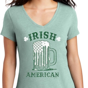 Op de afbeelding: Lichtgroen V-hals T-shirt met een afbeelding van een bierpul en de tekst "IRISH AMERICAN" in groen. Het bierpulontwerp bevat de Amerikaanse vlag.