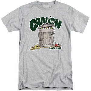 May include: A gray t-shirt with a green and white illustration of Oscar the Grouch from Sesame Street. Oscar is peeking out of a trash can with the text "Grouch" above him and "Since 1969" below him.