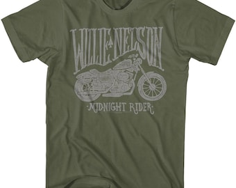 Puede incluir: Una camiseta verde con un gráfico blanco de una motocicleta y el texto "Willie Nelson Midnight Rider".