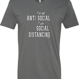 May include: A dark gray V-neck t-shirt with the text "I'm not anti social I am social distancing" printed in white.