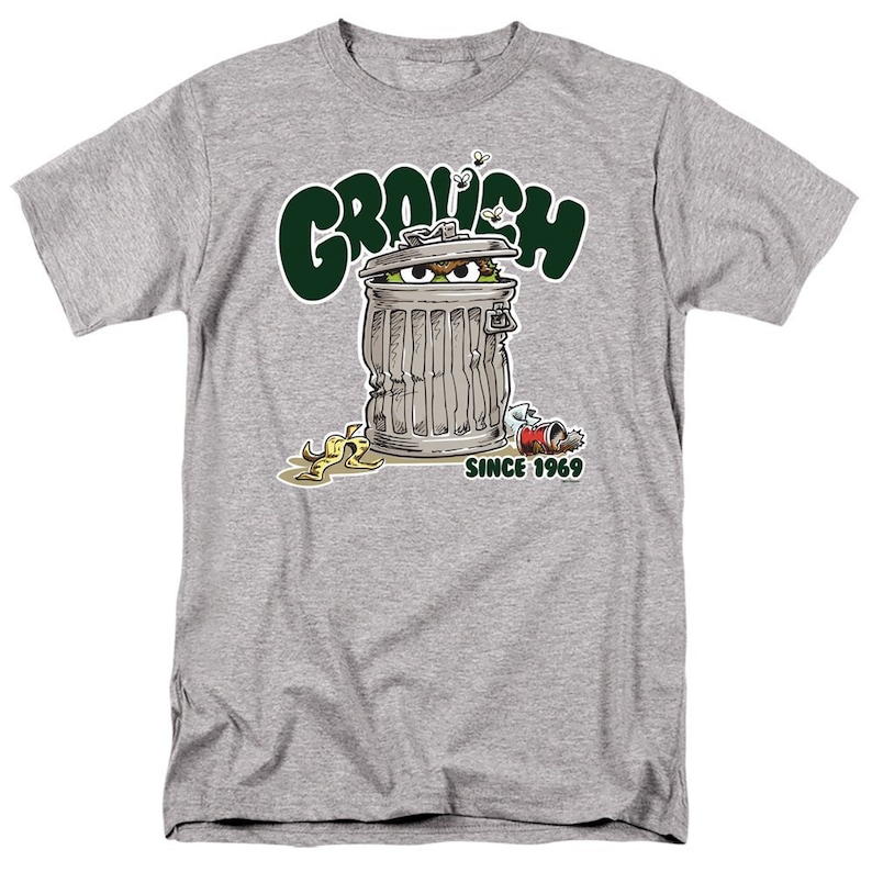 May include: A gray t-shirt with a green cartoon image of Oscar the Grouch from Sesame Street. The image shows Oscar inside a trash can with the text "Grouch" above him and "Since 1969" below him.